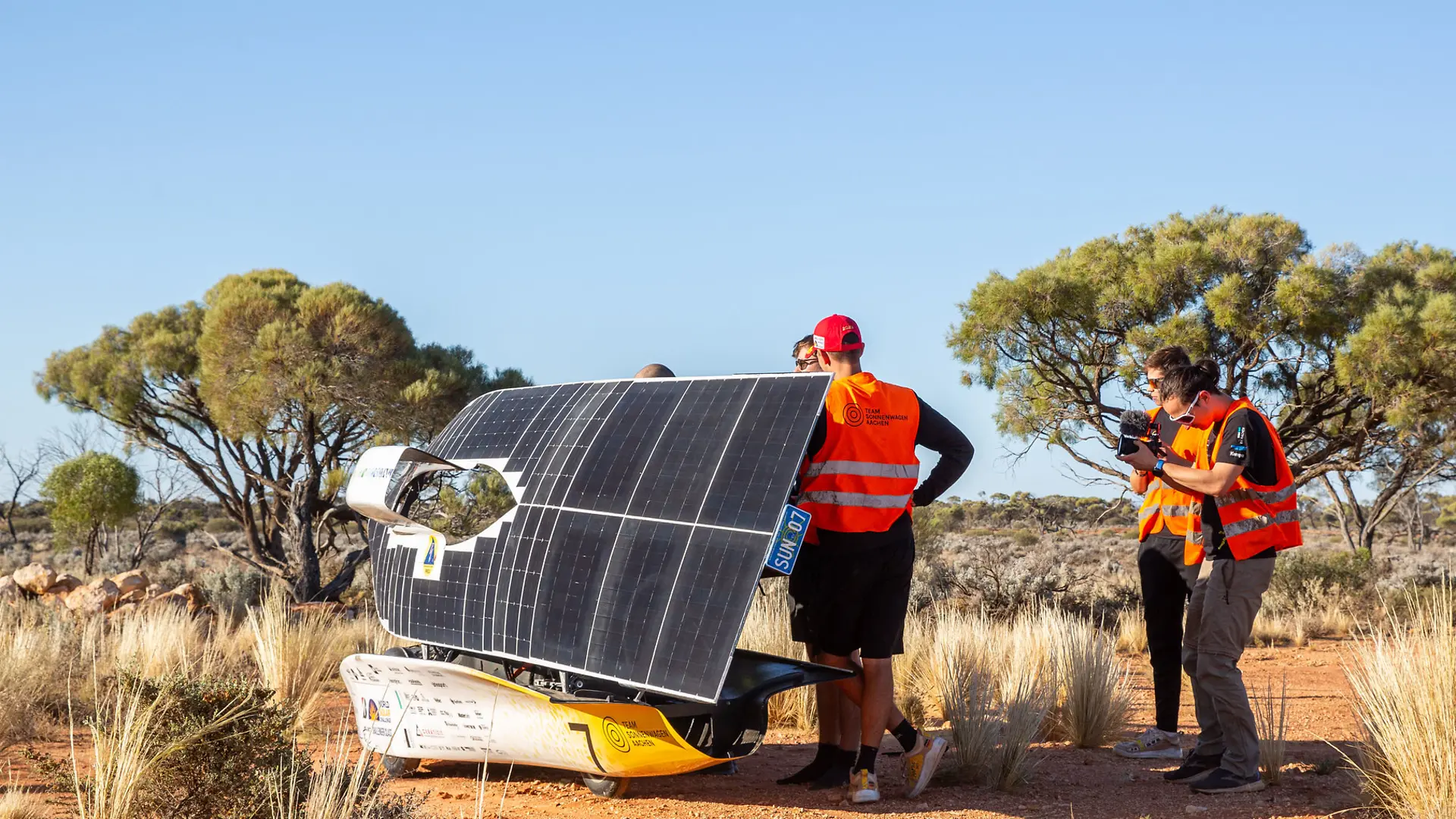 The Sonnenwagen is positioned sideways in a desert-like environment with sparse vegetation and a clear blue sky.