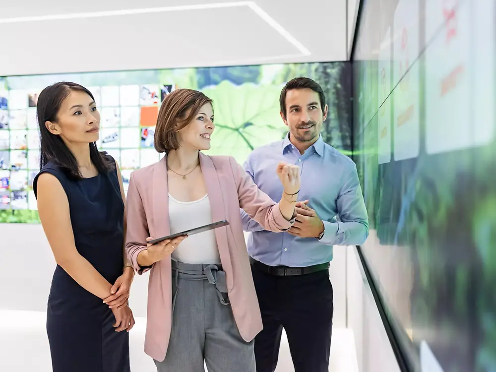 A customer experience tour guide is presenting the Adhesive Technologies portfolio to a group of customers in the 270° Infinity Room at the Inspiration Center Düsseldorf.